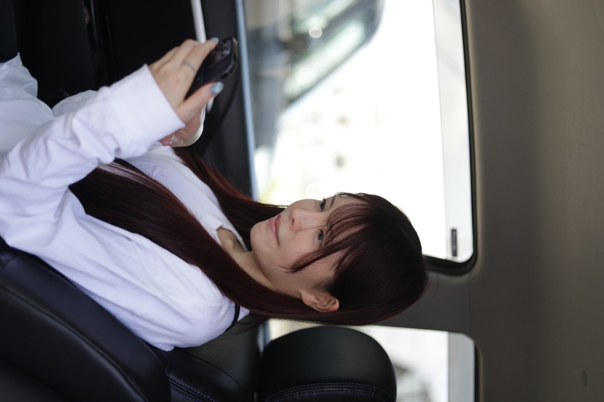 車内でスマホからレッスンを予約する女性会員