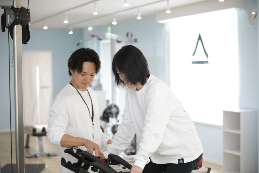 トレーナーがマシンの重量を設定する様子